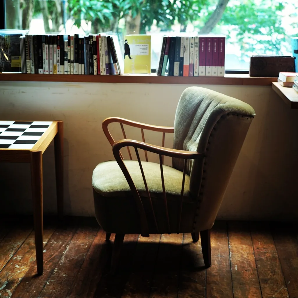 Kanso lounge chair — an oiled solid-wood armchair beside a bookshelf