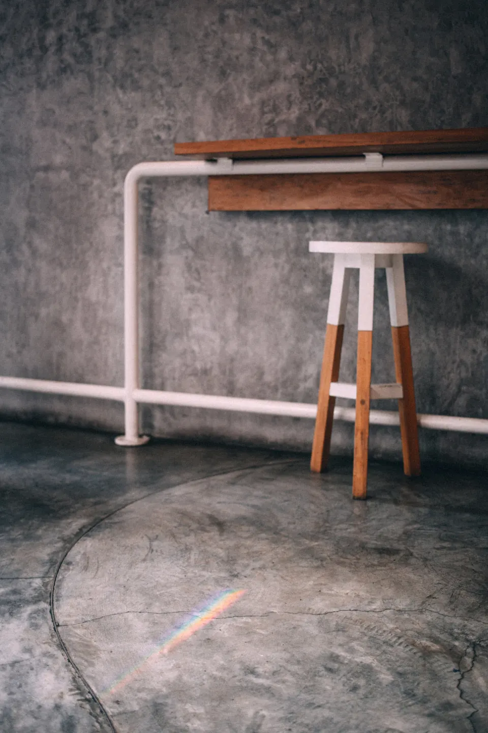 Koshi stool — a carved solid-ash stool against a raw plaster wall